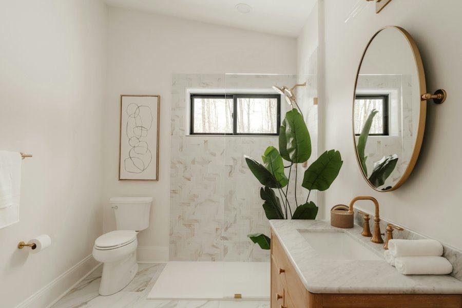 A bright renovated bathroom with a wood vanity, round mirror and tiled shower